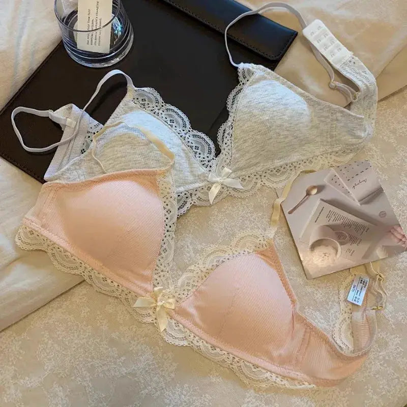 Two SP&CITY lace women's bras, pink and white, wire-free triangle cups with scalloped lace trim and bow accents.