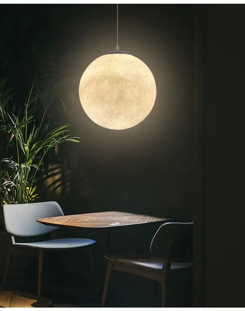 Nordic Moon LED pendant light by Simples Market, warm glow over dining table in cafe setting.