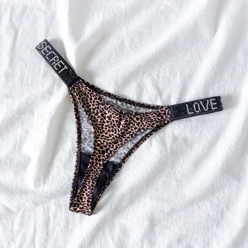 Leopard print low-rise thong with rhinestone-embellished black straps reading LOVE