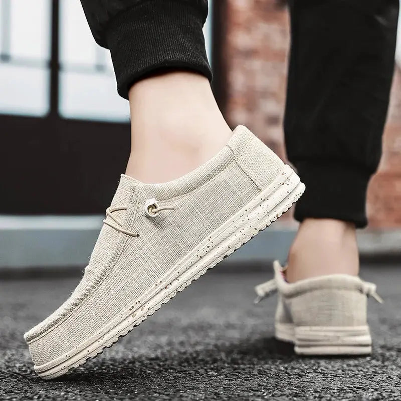 Pair of men's casual canvas loafers in light beige with lace-up detail and speckled sole