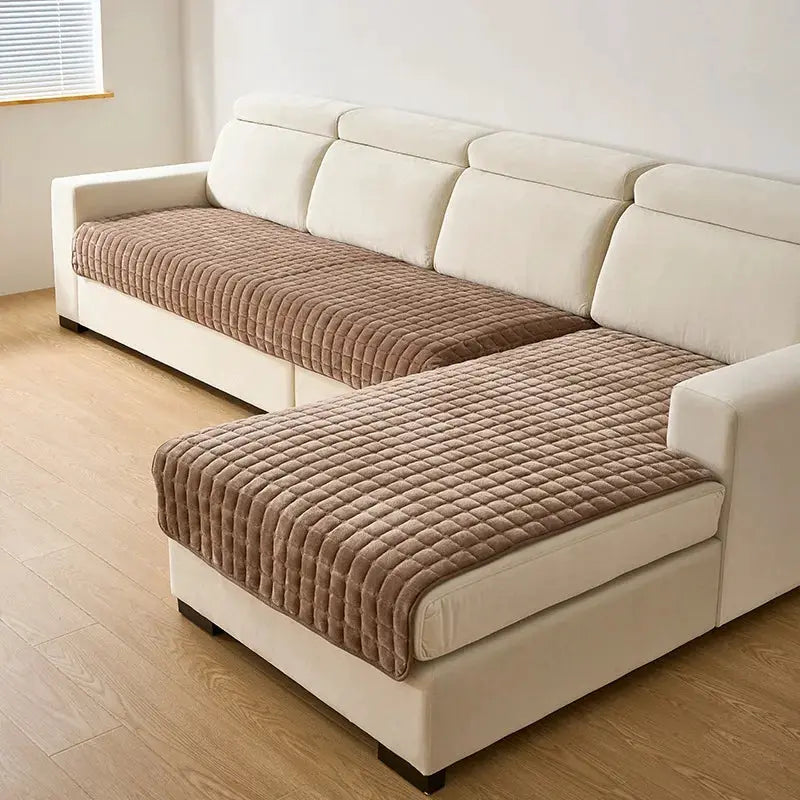 Flannel plaid sofa cover on beige L-shaped sofa; two brown quilted, non-slip seat covers.