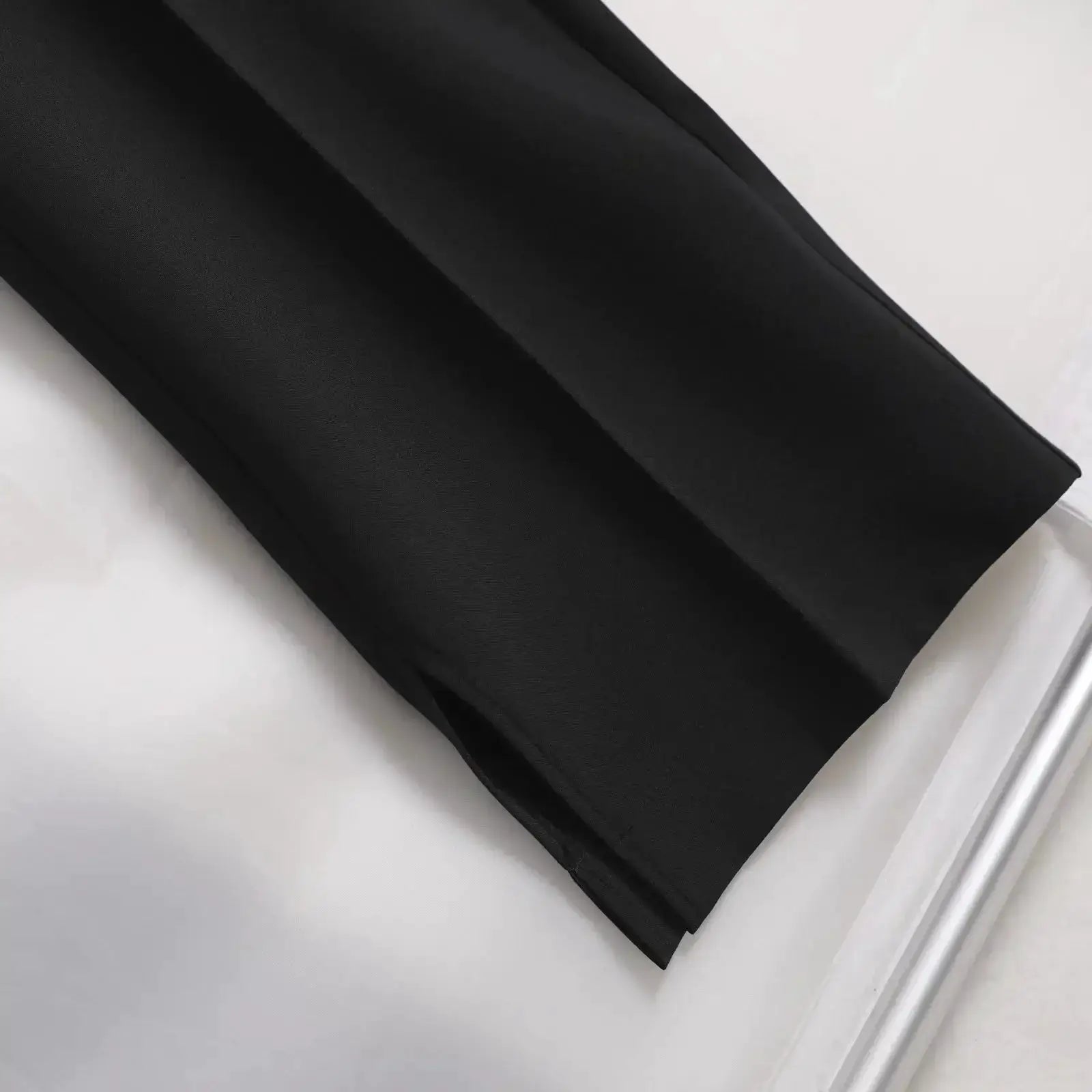 Men's black straight baggy trousers close-up of smooth fabric and neat hem edge