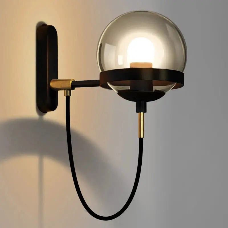 Modern glass ball wall lamp; black metal arm with brass accents, E27 bulb