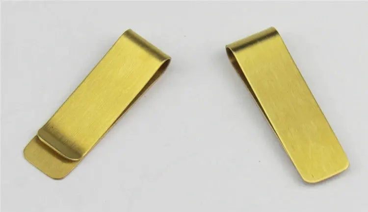 Two gold-toned metal money clips on a white background.