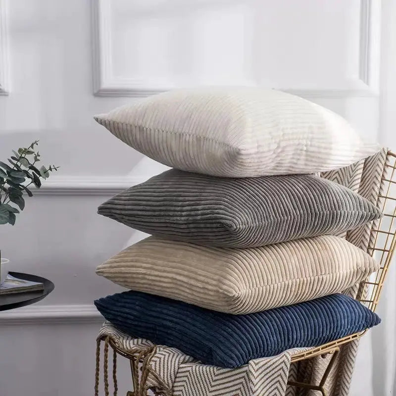 Corduroy pillow covers by Simples Market in white, gray, beige and navy, four stacked on a chair