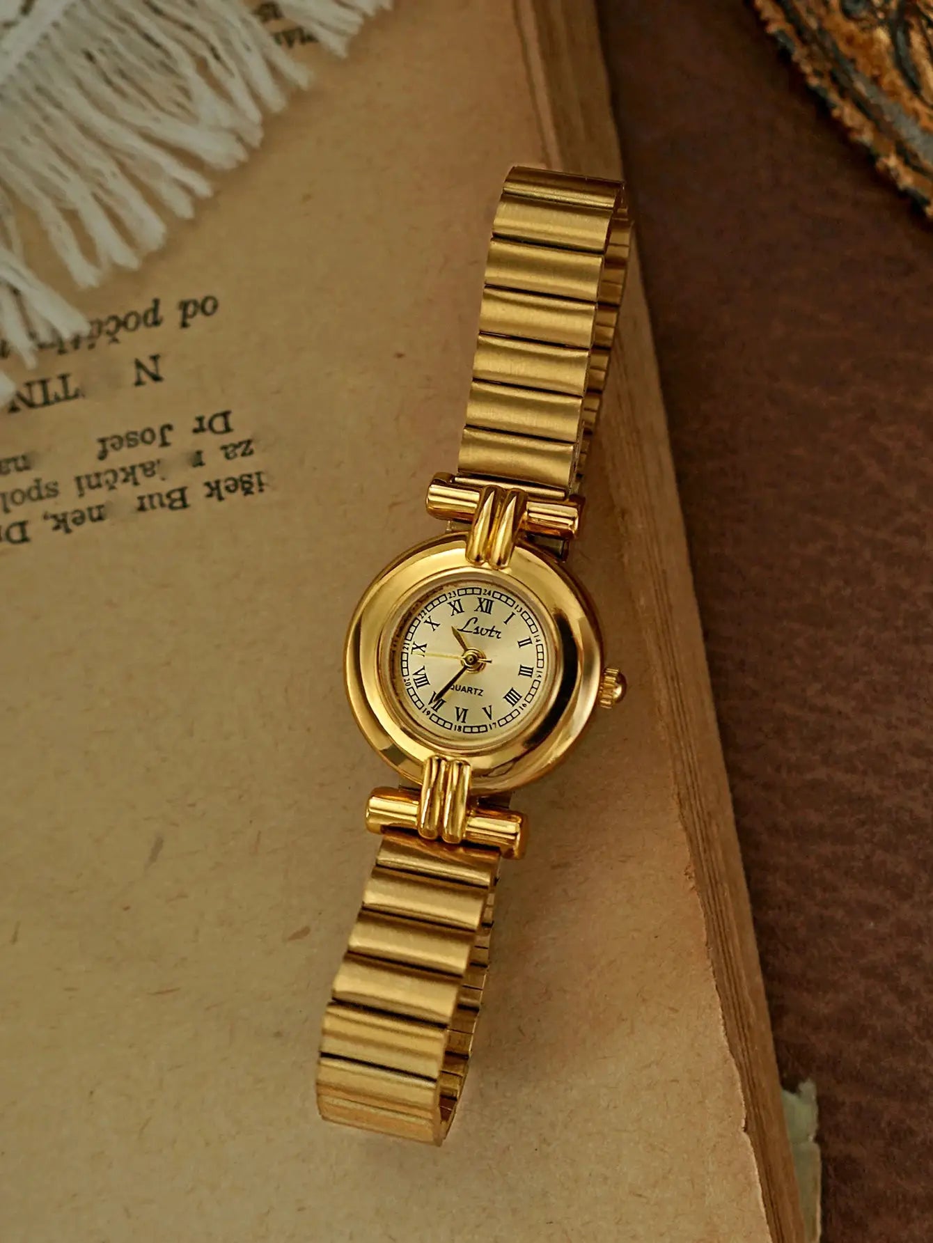 Gold-tone women's wristwatch with a small Roman-numeral dial and a linked bracelet
