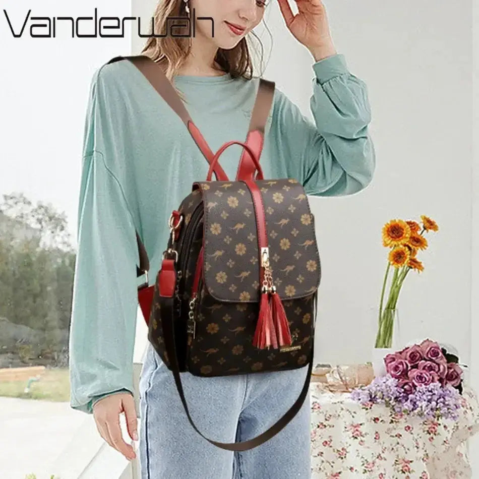 Backpack by Simples Market; brown leather-style bag with monogram print, red straps and tassel, large capacity