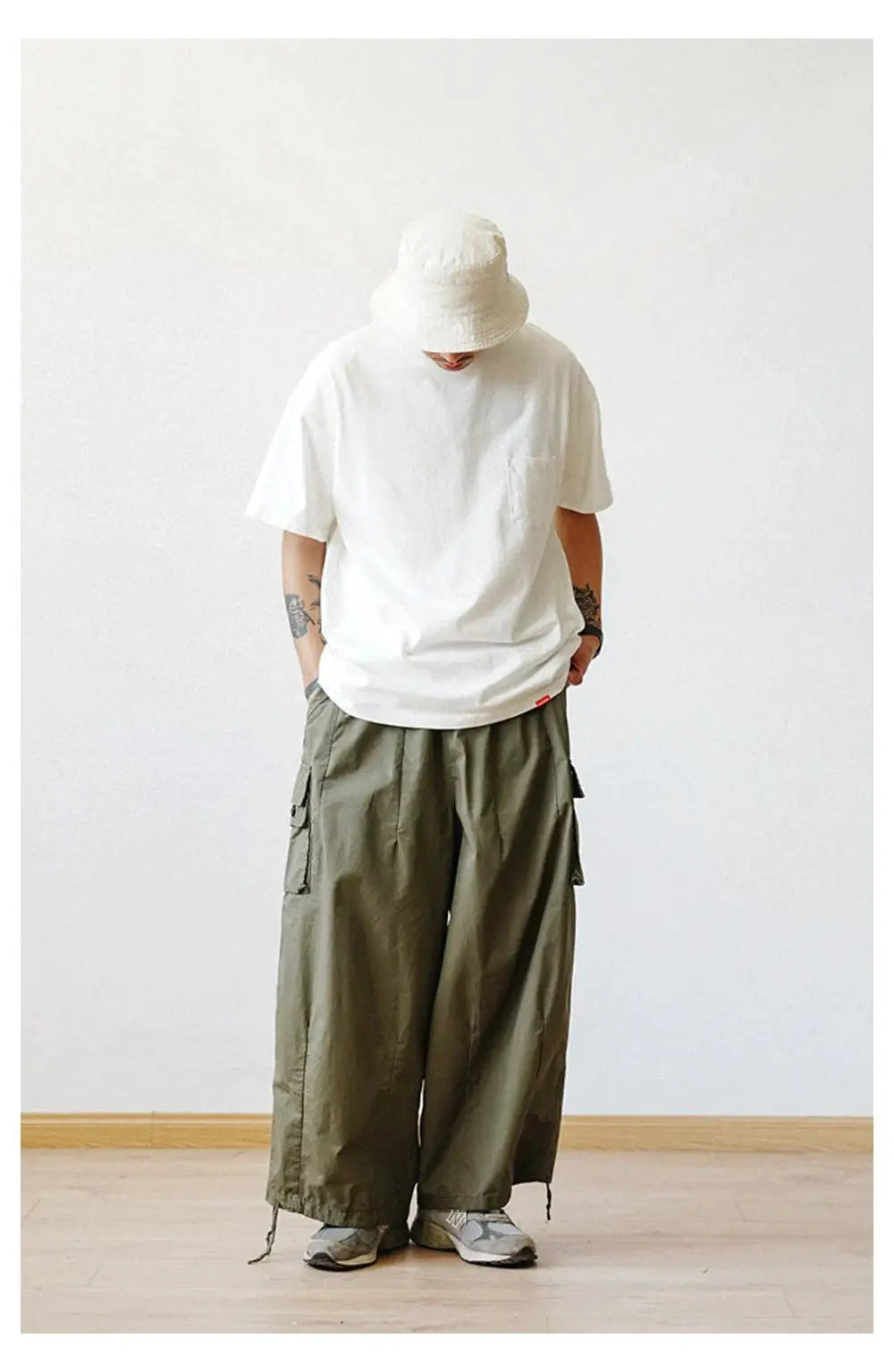 Men's multi-pocket oversized cargo pants in olive green with wide legs and drawstring cuffs.