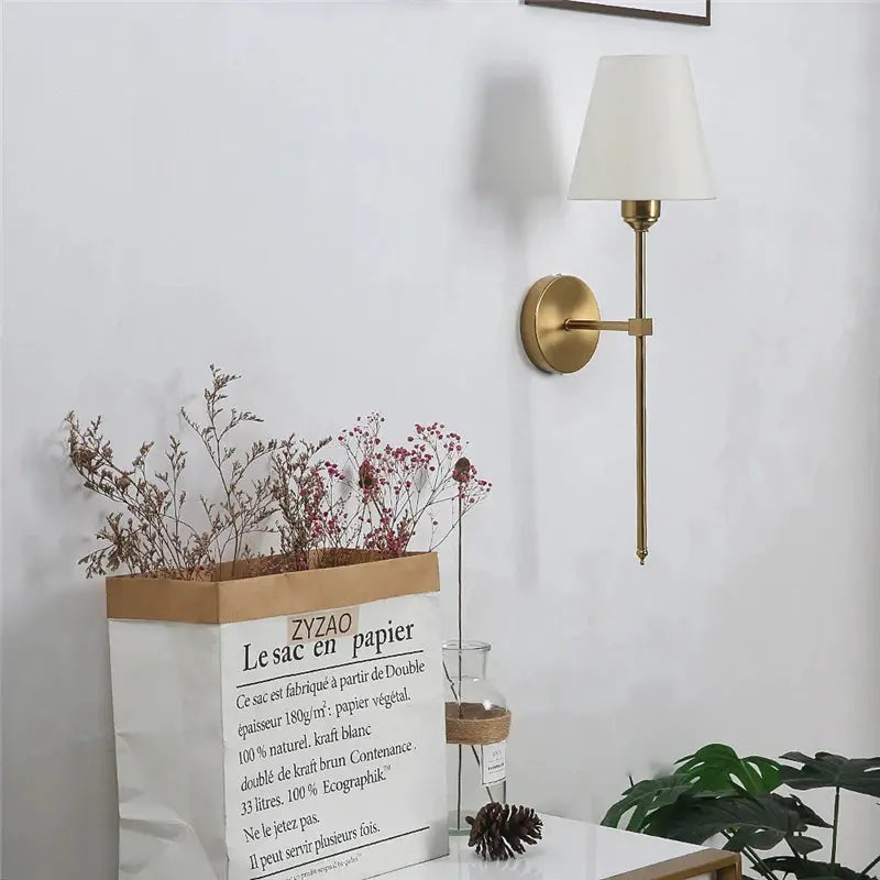Brass finish wall sconce with white fabric shade, modern bedroom lighting