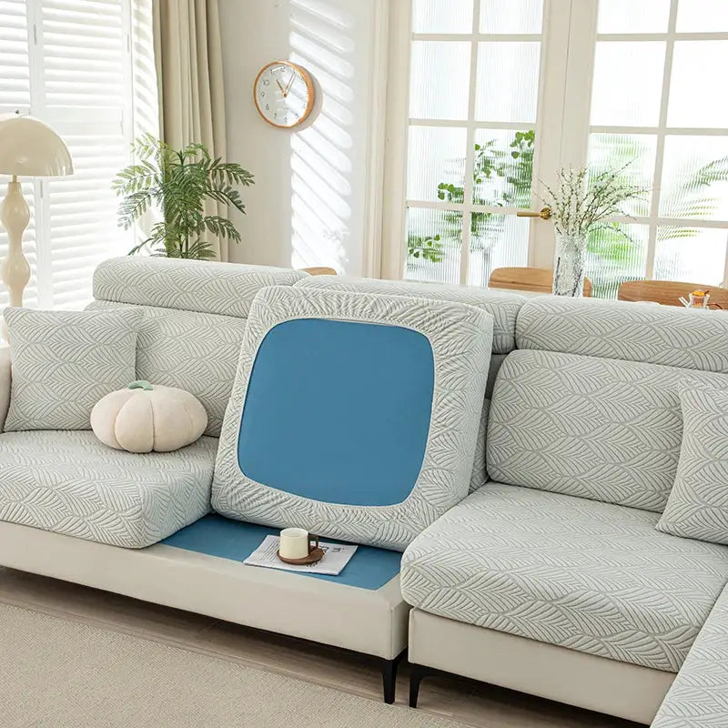 Sofa cover set by Simples Market; light grey leaf-pattern cushions with blue panels on a living room sectional