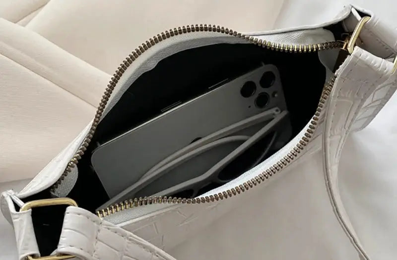 Underarm handbag in white alligator-pattern PU leather with gold zipper; compact size with phone inside.