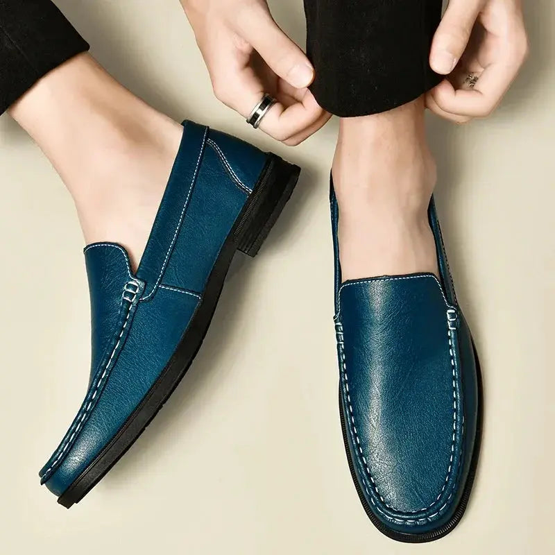 Pair of blue leather men's slip-on dress loafers with white stitching and black soles.