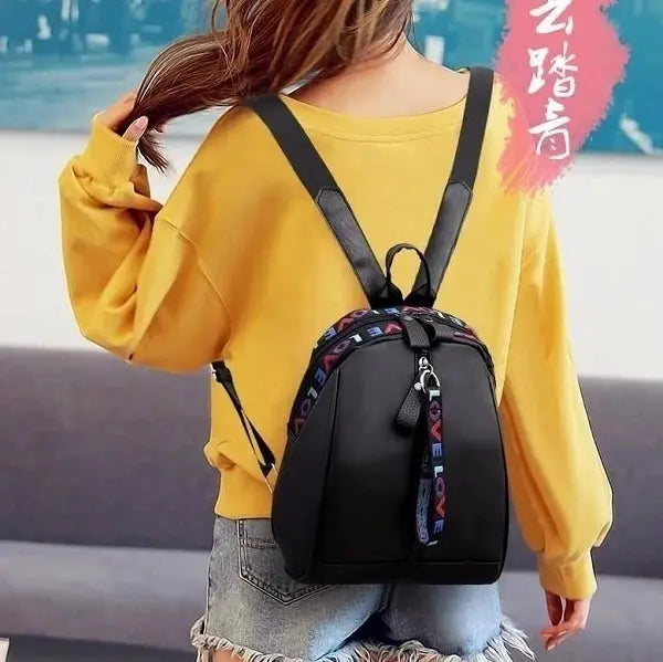 Women's black backpack with LOVE-strap, worn by model in a yellow top