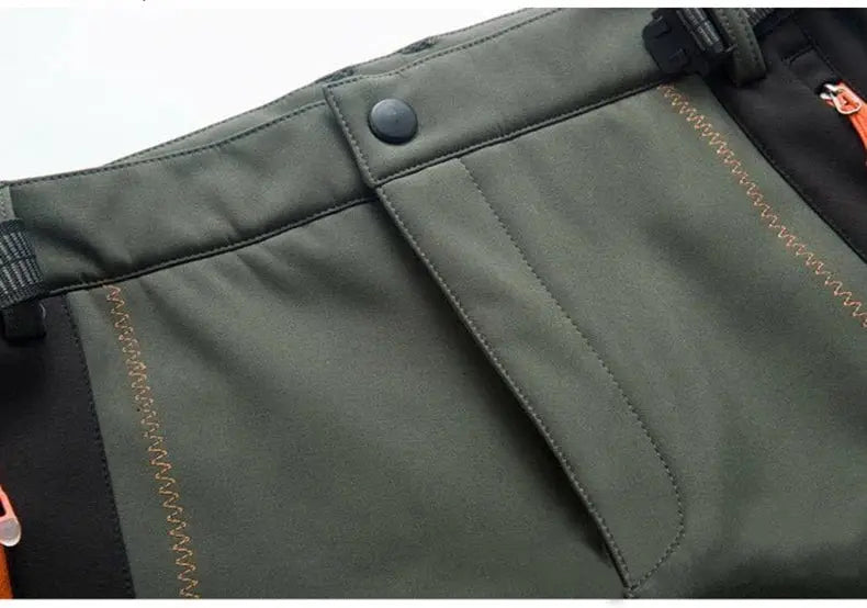 JNLN olive green hiking pants with orange topstitching, snap waist button, and side zipper pull