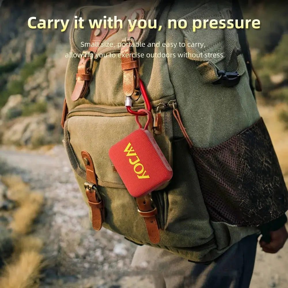 G04 red mini Bluetooth speaker clipped to a khaki backpack outdoors