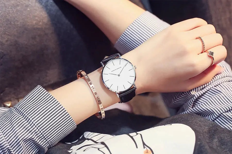 Hannah Martin women's wristwatch with white dial, silver case, black leather strap, paired with a rose-gold bracelet.
