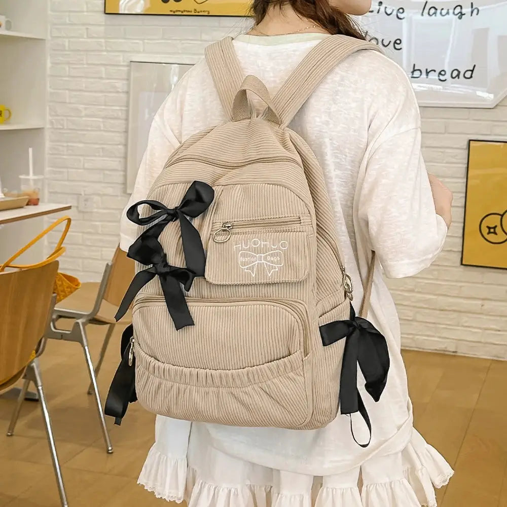 Backpack beige corduroy with black bow accents and front zip pocket for commuting and college use