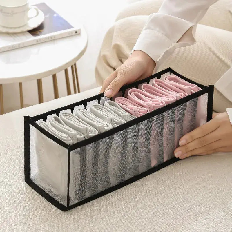 Black-framed mesh clothes organizer box holding folded socks in white, gray and pink