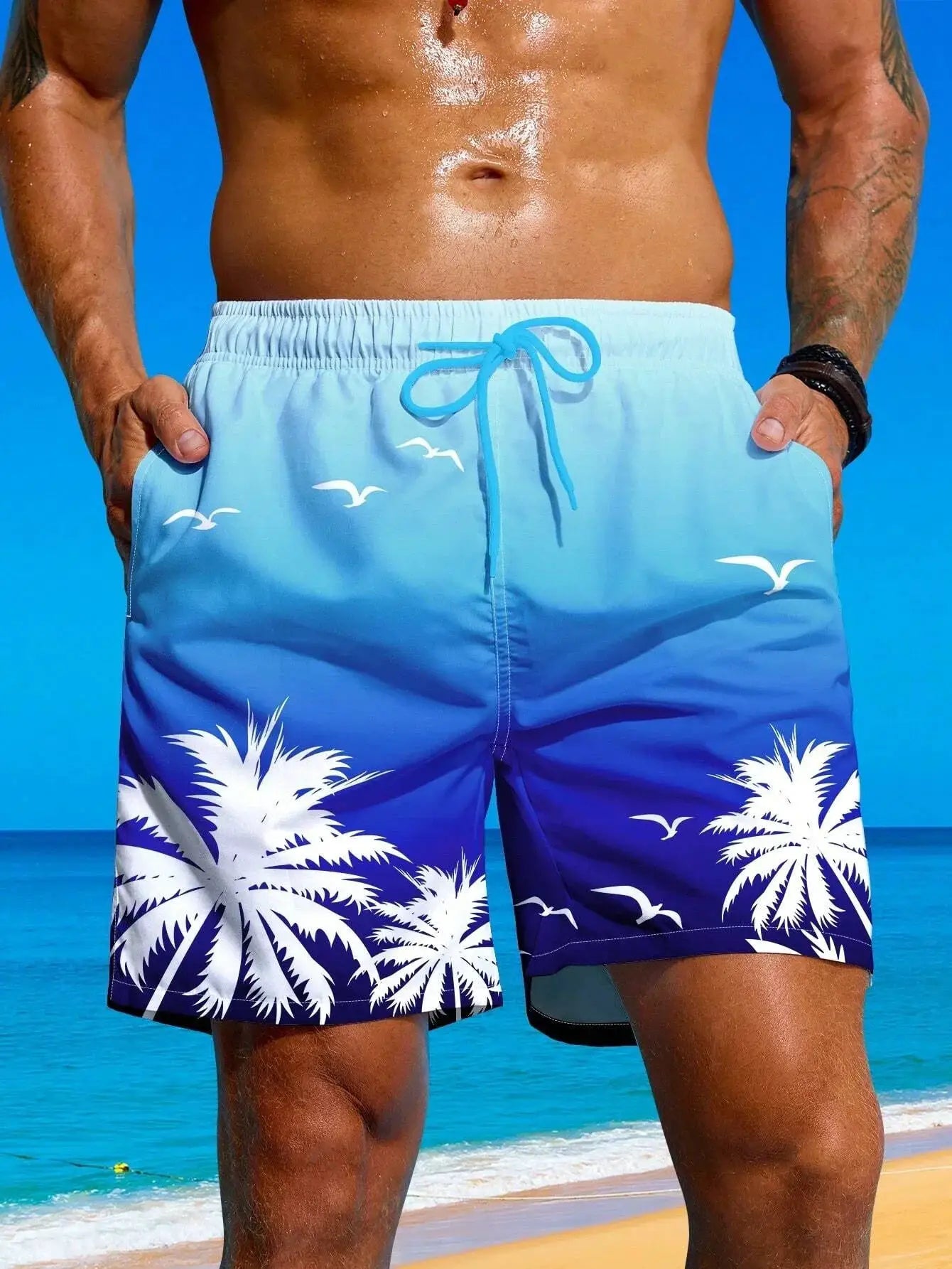 Men's blue gradient board shorts with white palm tree and bird print, adjustable drawstring waist.
