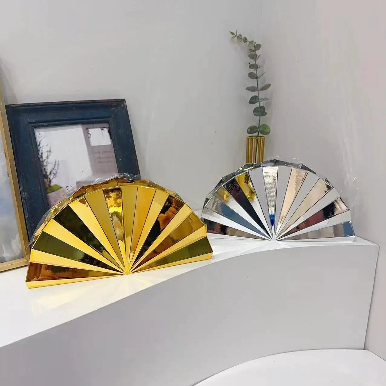 Two moon-shaped acrylic box purses in gold and silver, fan-style hand-held evening bags.