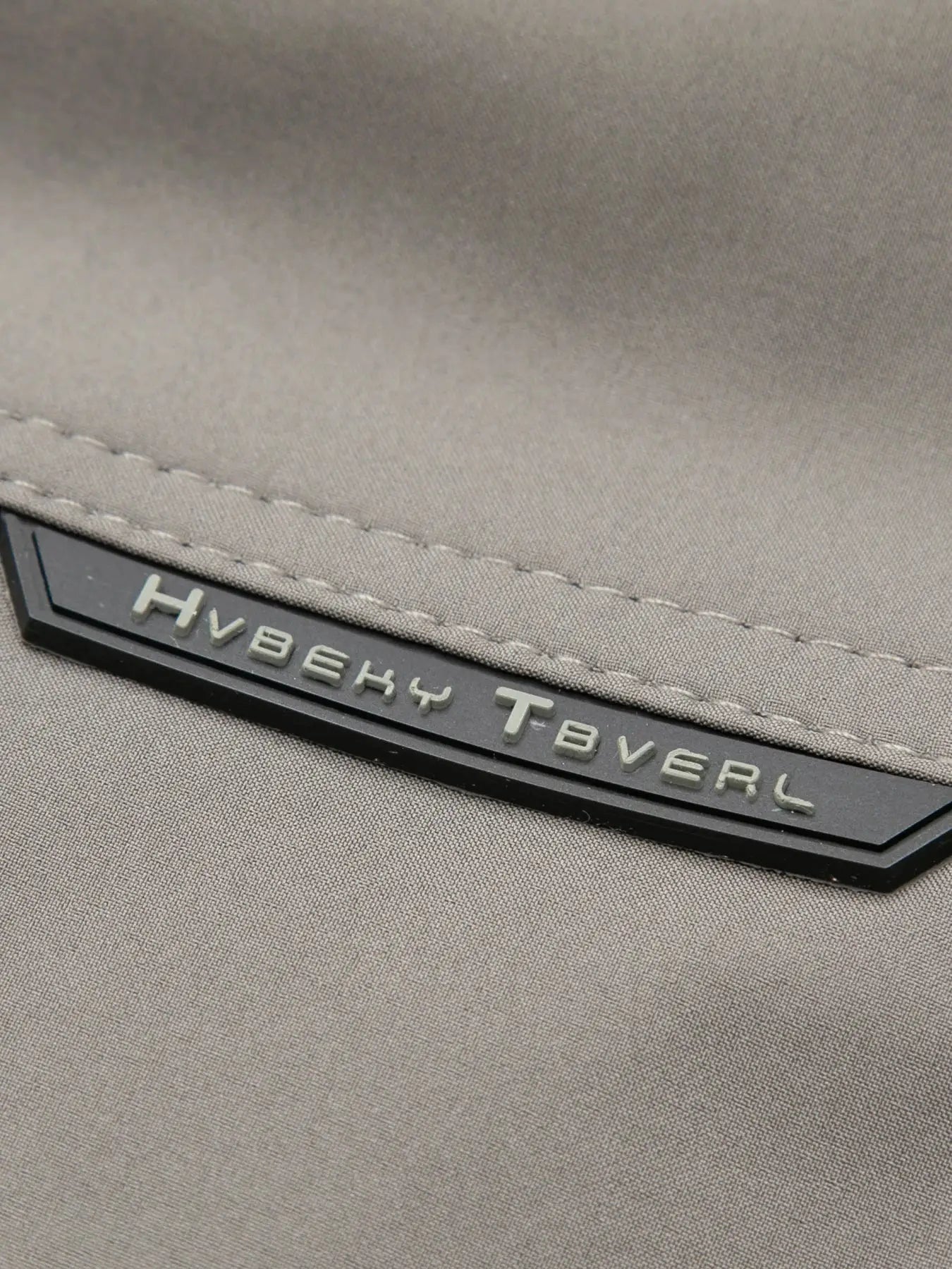 Men's cotton jacket, khaki color, close-up of stitched hem and metal badge