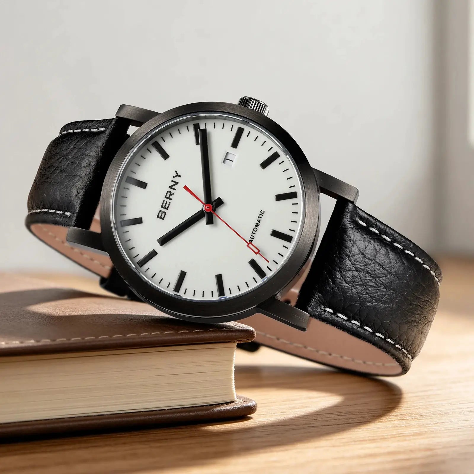 BERNY men's automatic watch with white dial, dark metal case, and black leather strap with white stitching.