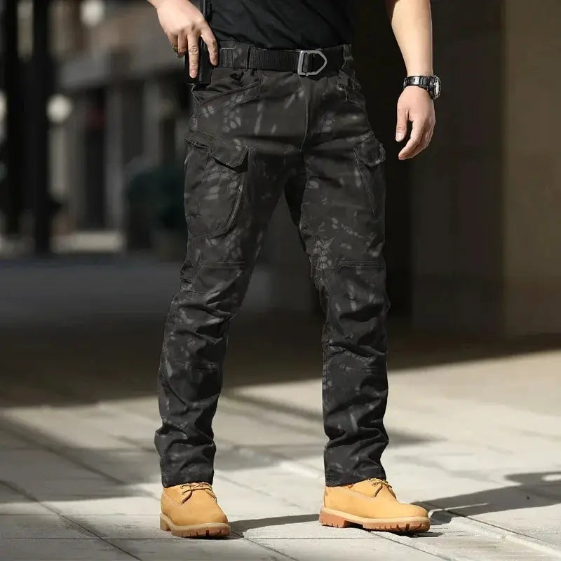 Men's tactical cargo pants in black camo, belted waist, softshell stretchy fabric and multiple cargo pockets with flaps