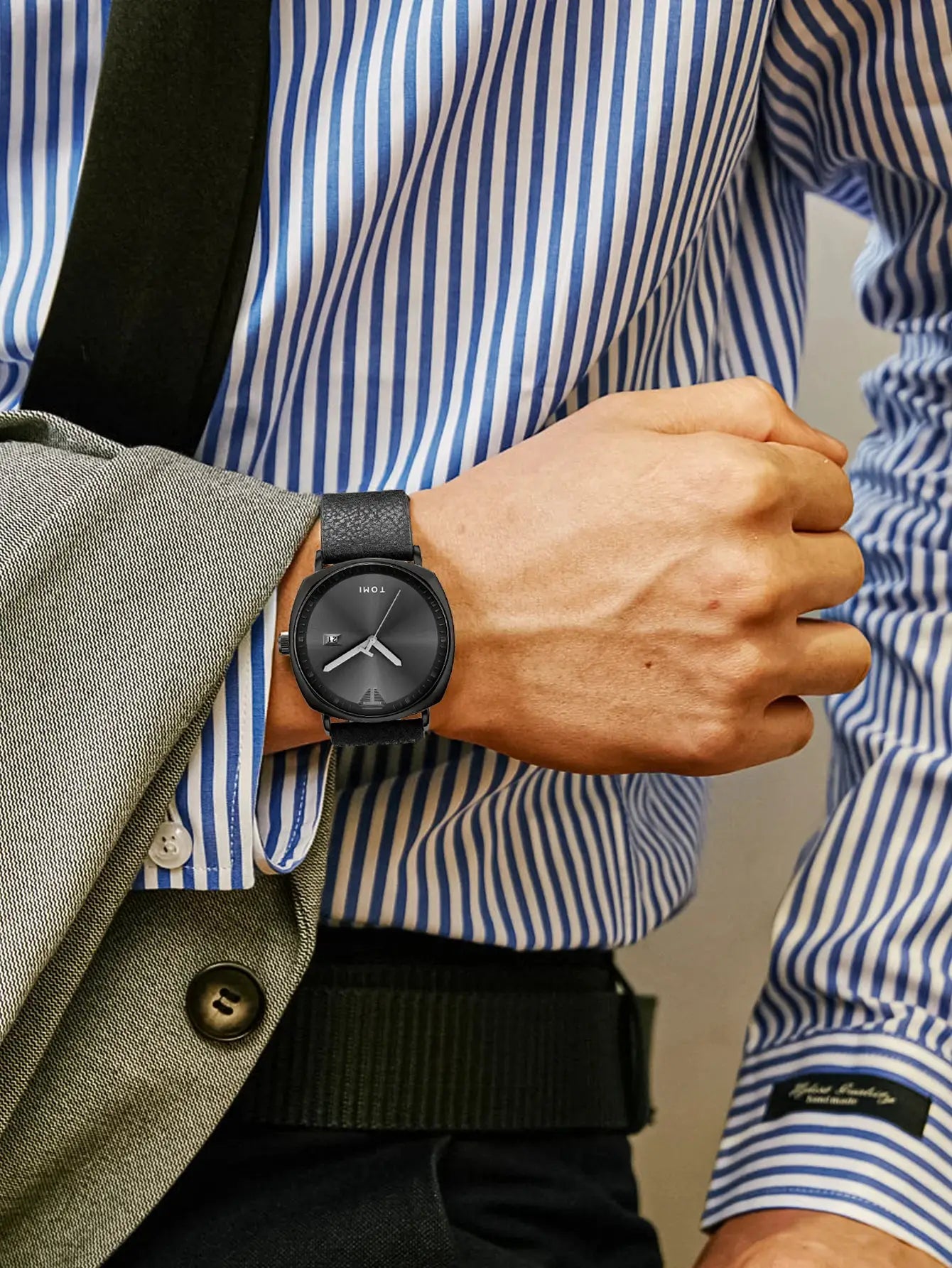 TOMI men's minimalist leather watch with black dial and calendar on the wrist.