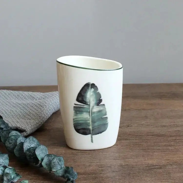 White ceramic bathroom cup with green leaf print by Simples Market