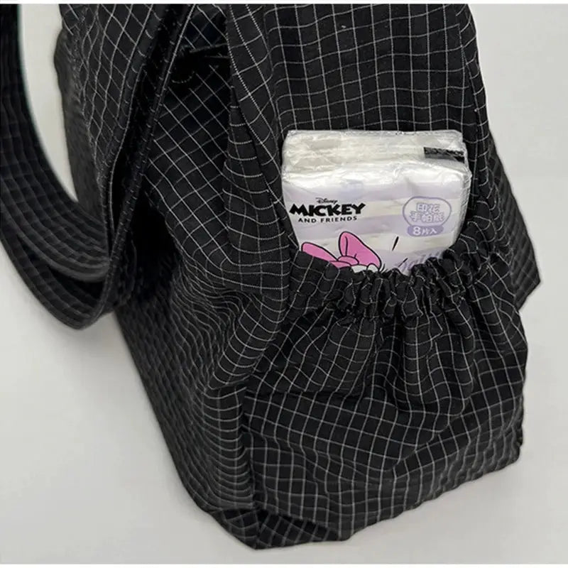 Black plaid nylon shoulder bag with elastic side pocket holding a tissue pack.
