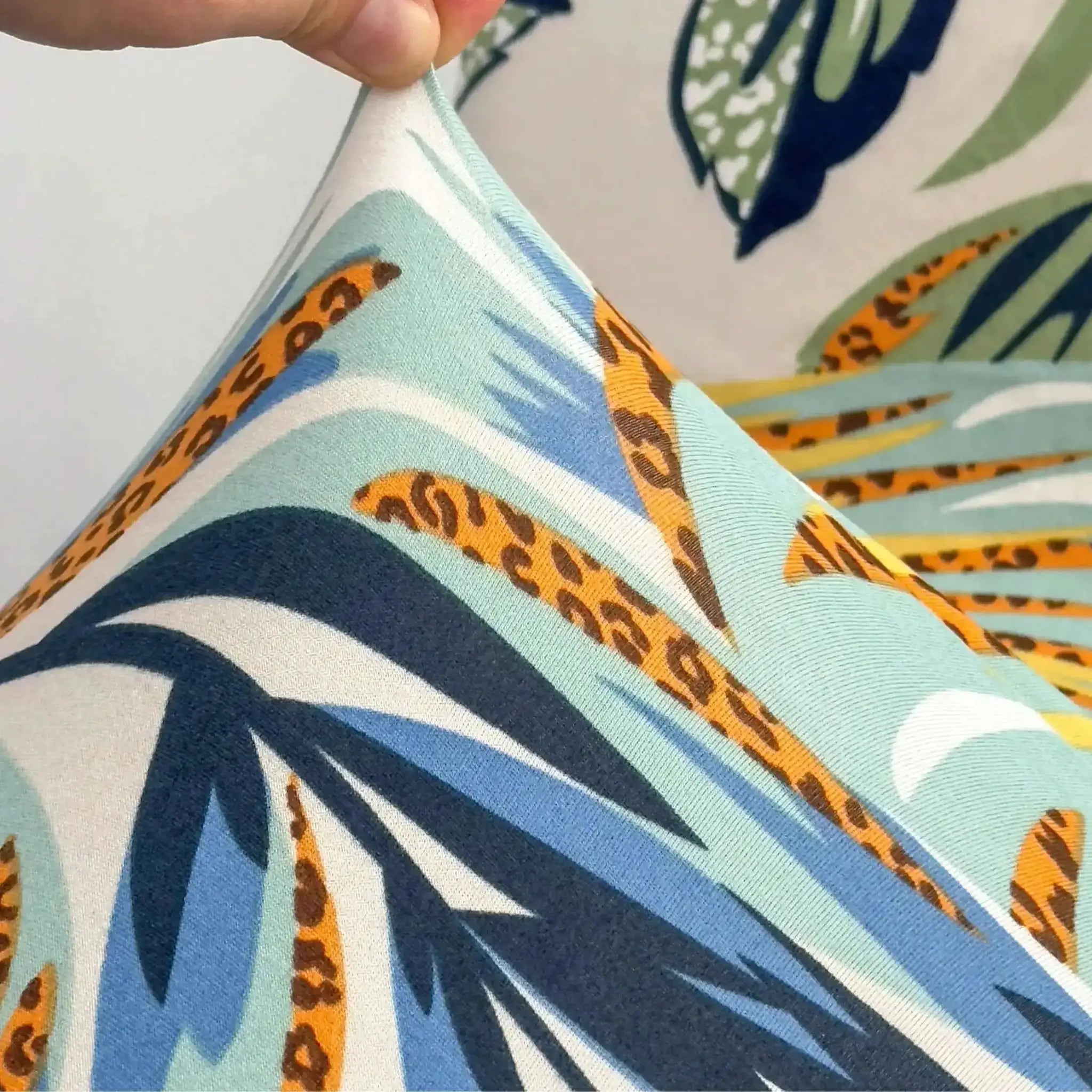 Outdoor tropical print sofa cushion cover; turquoise/blue background with orange leopard-spot edge pattern