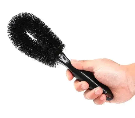 Car wheel cleaning brush with black bristles and ergonomic black handle.