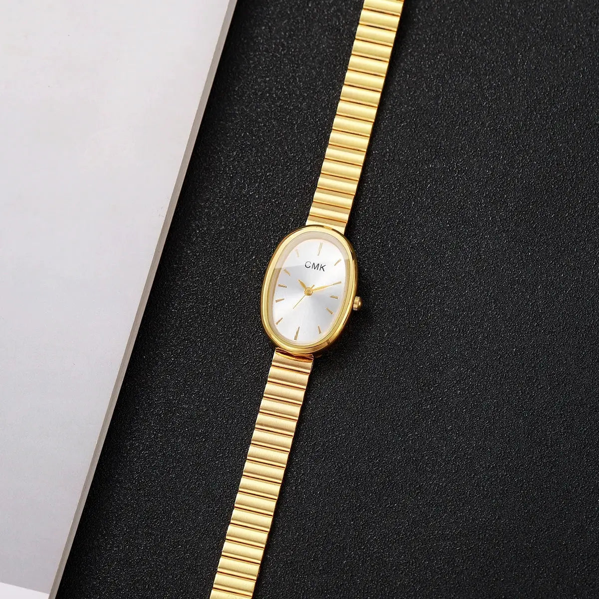 Gold-tone women's oval-dial wristwatch with slim metal bracelet and CMK dial, quartz movement.