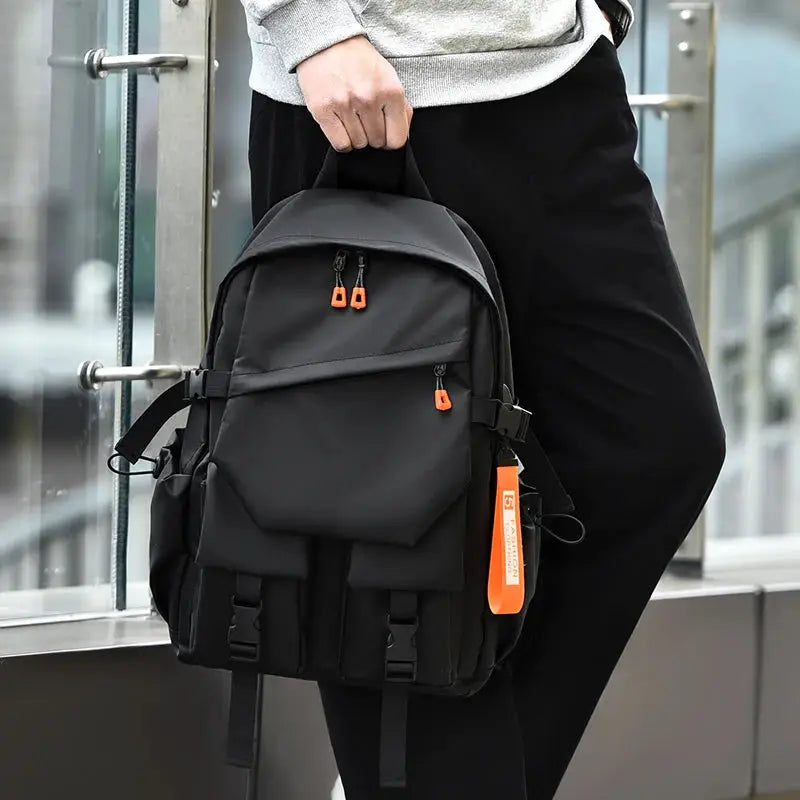 Simples Market black men's backpack with multiple pockets, orange zipper pulls, and orange tag.