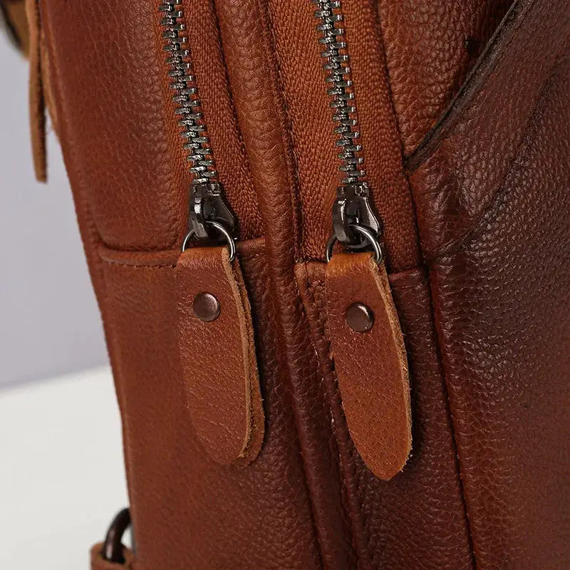 Brown leather chest bag with dual zippers and leather zipper pulls