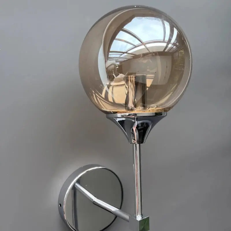 Modern glass wall sconce with amber globe and chrome mounting.