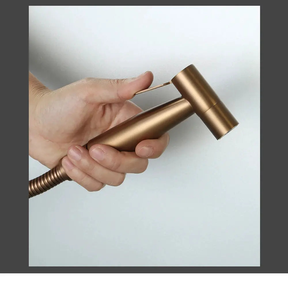 Handheld bidet sprayer head in brushed rose gold stainless steel with a coiled hose