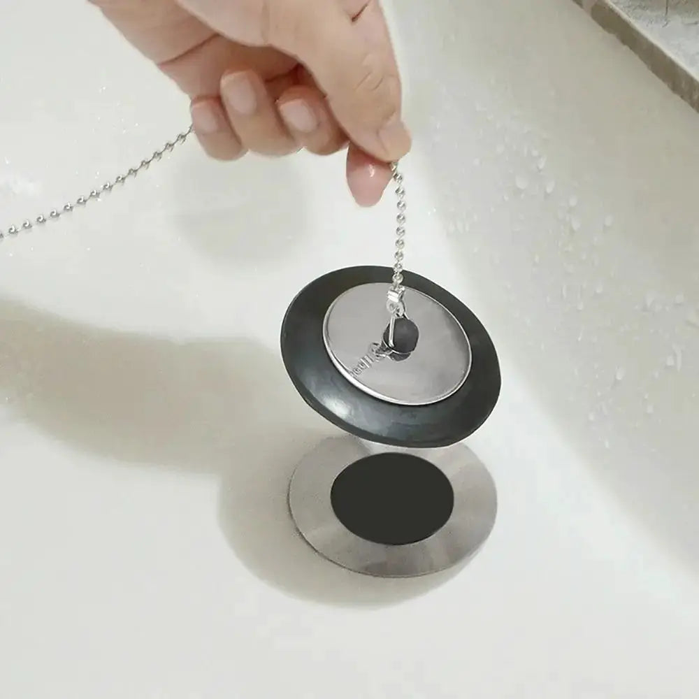 Tub stopper with chain for universal bath drain; black rubber seal with silver metal plug and hanging ring.