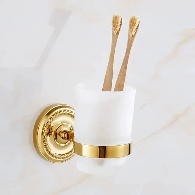 Gold brass wall-mounted toothbrush holder with frosted white cup and two wooden toothbrushes