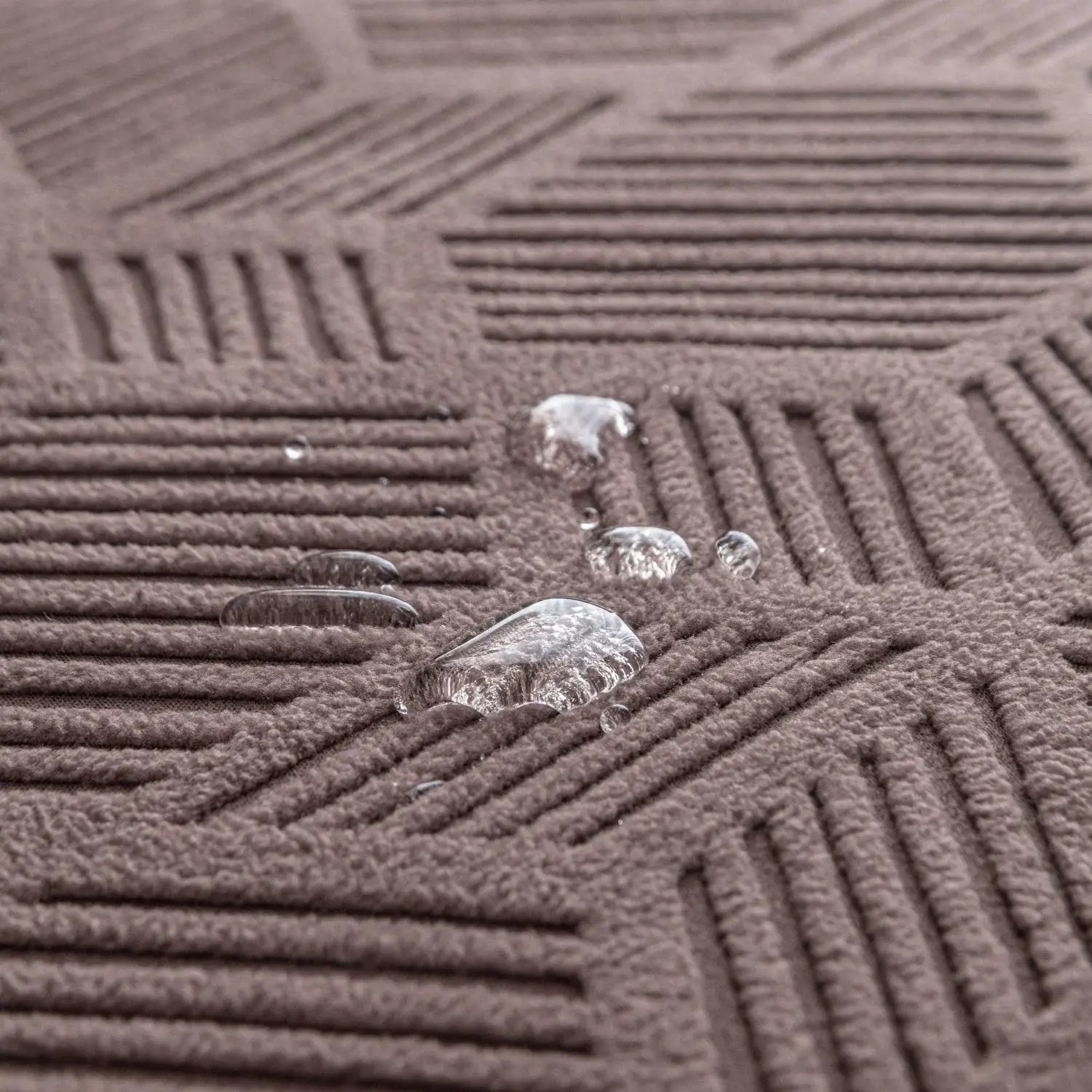 Jacquard stretch sofa cover fabric in brown with water droplets on a textured surface
