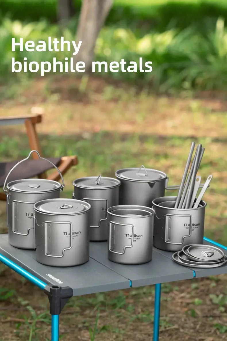 Tiartisan titanium camping mug set with folding handles and lids displayed on a portable camp table