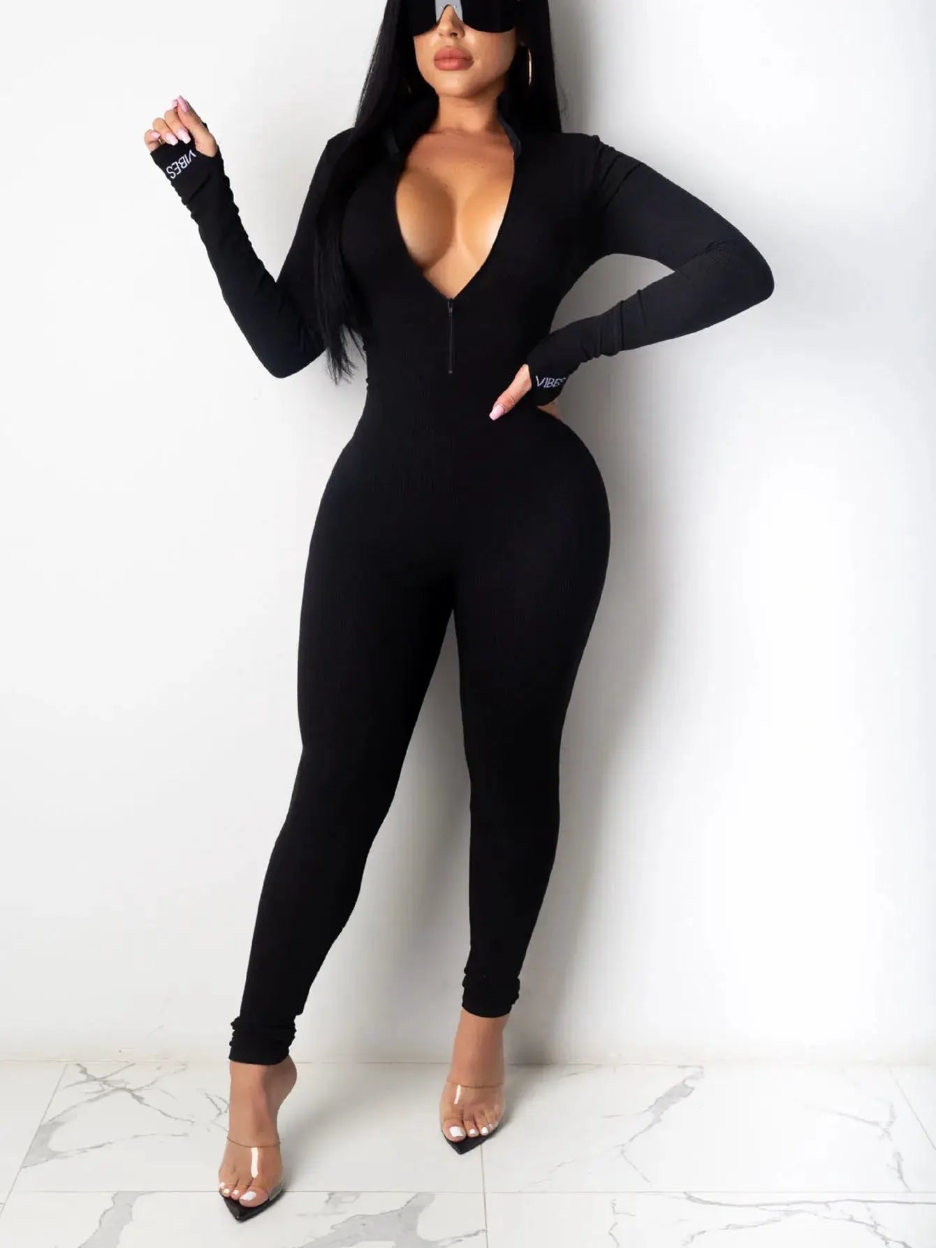 Black ribbed-knit long-sleeve jumpsuit with front zipper, form-fitting women's outfit.