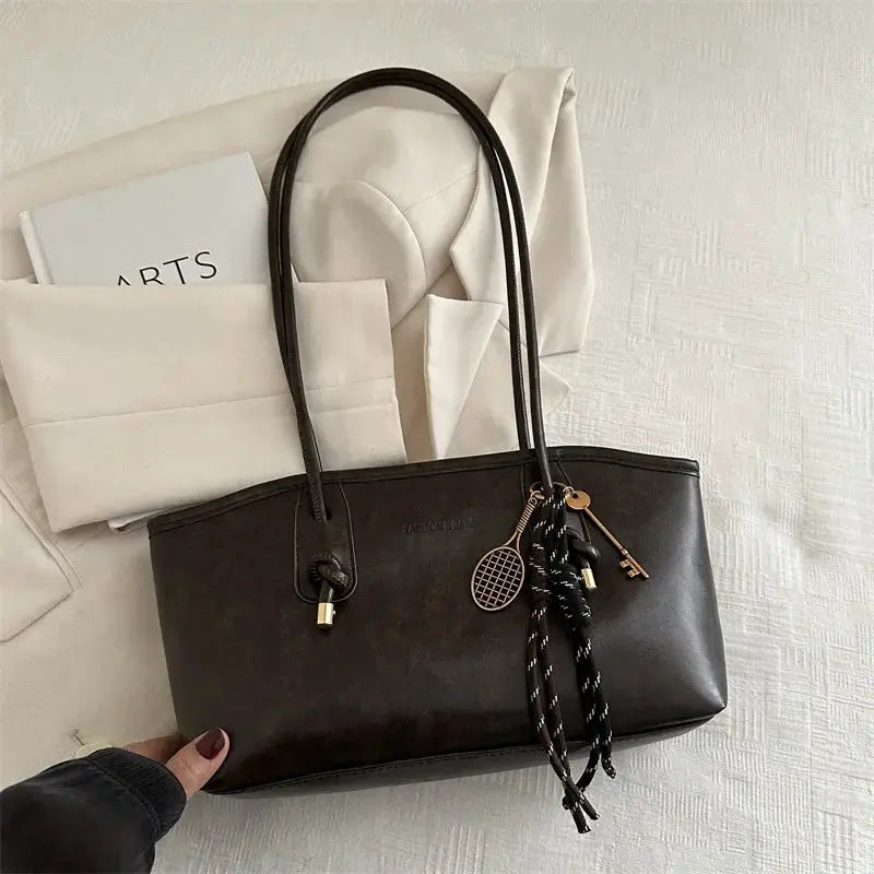 European American retro tote bag by Simples Market in dark brown leather with dual top handles and pendant charms
