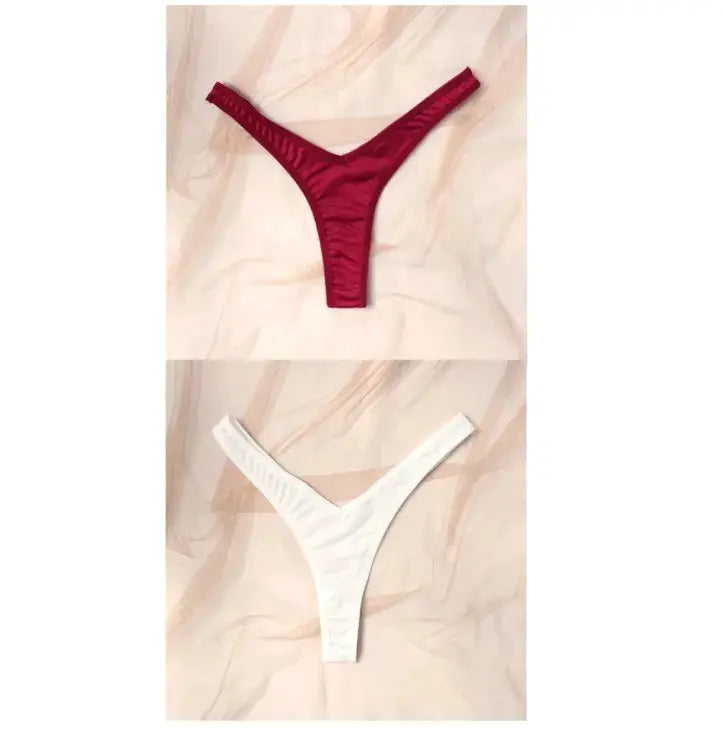 Two-pack low-rise thong underwear in red and white on beige fabric backdrop.