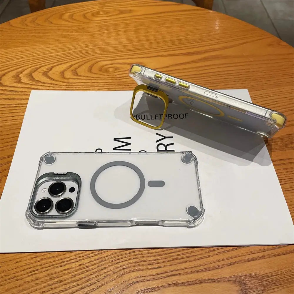 Simples Market clear MagSafe phone case with yellow ring stand; two transparent iPhone cases on a wooden table.