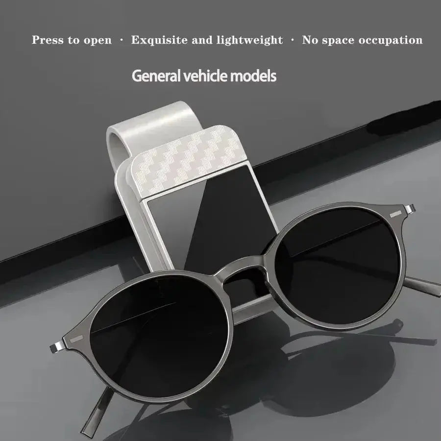 Car sun visor sunglasses clip with ticket/card holder; metal finish and round black frames.