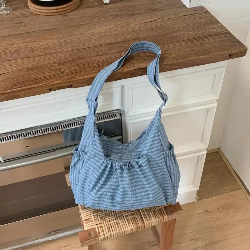 Blue plaid nylon shoulder bag with gathered top and drawstring closure, casual tote style