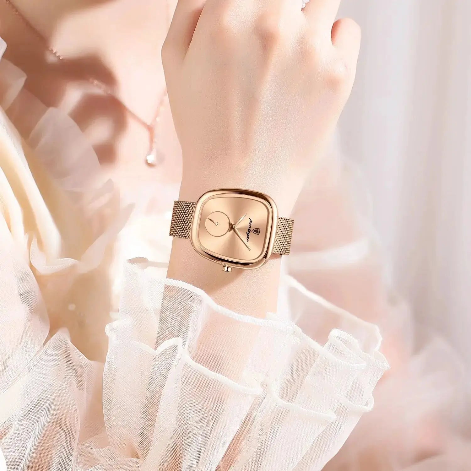 POEDAGAR luxury women's rose gold stainless steel mesh wristwatch on a wrist with sheer white fabric