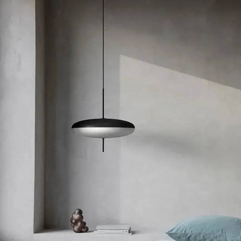 Nordic LED pendant light with flying saucer design in black and white, suspended over a minimalist bedroom setup.