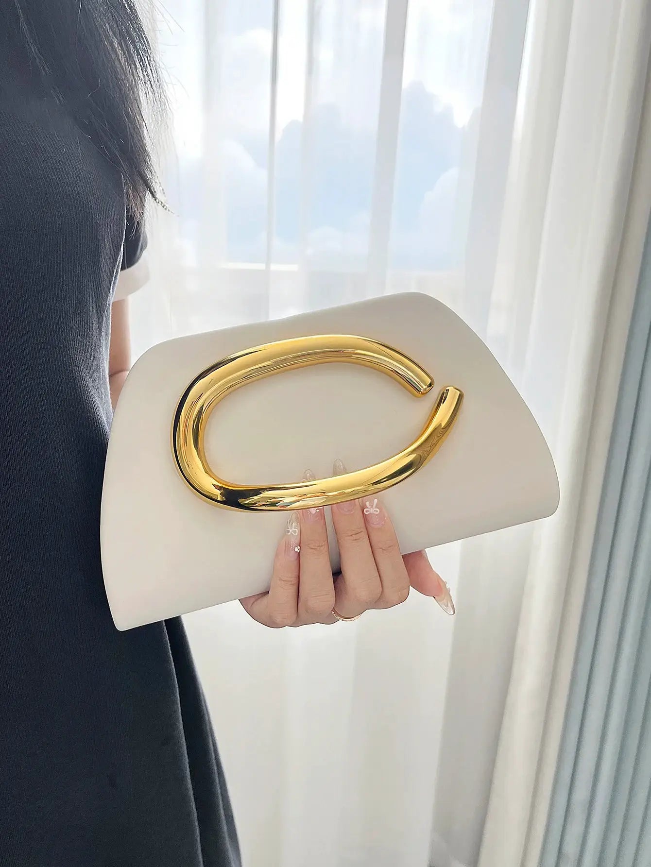 Ivory box clutch featuring a large gold curved buckle, luxury evening bag
